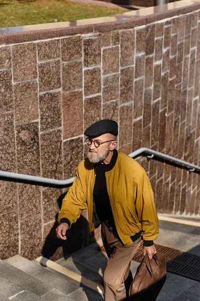 A fashionable older man ascends city stairs, exuding confidence and style. — Stock Photo