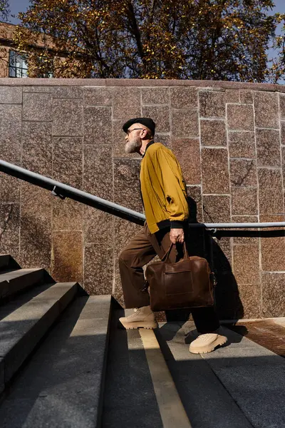 A senior man walks up stone steps in a stylish outfit, showcasing his modern sense of fashion. — Stock Photo