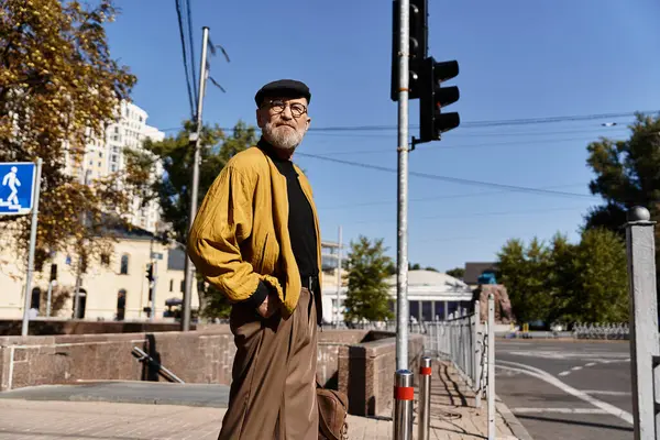 A stylish senior man walks through an urban environment, showcasing his impeccable fashion sense. — Stock Photo