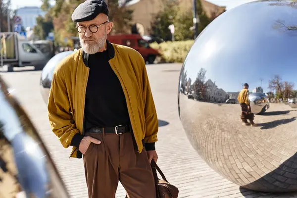 A senior man strolls confidently through a cityscape, complemented by shiny modern sculptures. — Stock Photo