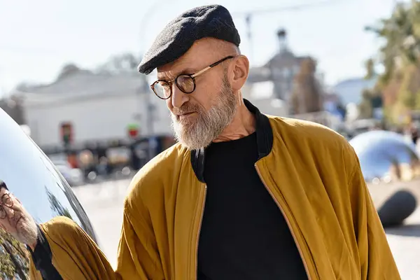A senior man in a fashionable bomber jacket and chic accessories walks through a lively city. — Stock Photo