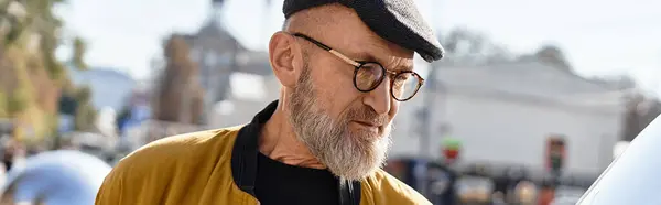 A fashionable senior man confidently walks through the bustling city, showcasing his trendy style. — Stock Photo
