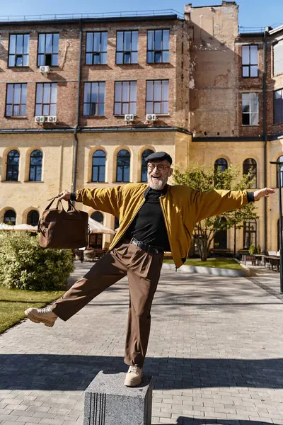 A handsome senior man, in trendy attire, strikes a playful pose on block in a vibrant cityscape. — Stock Photo