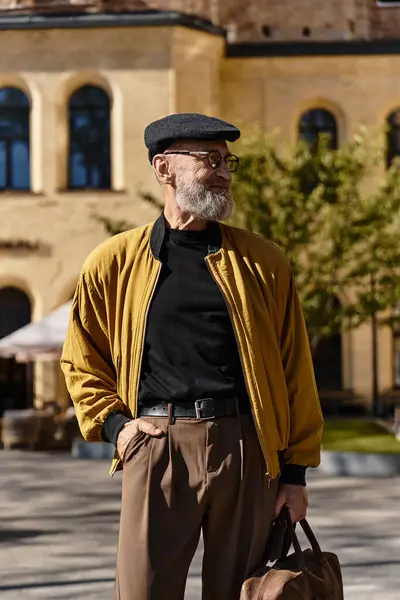 An attractive senior man, dressed in chic attire, confidently walks through an urban setting. — Stock Photo