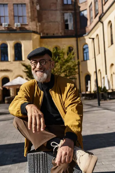 A fashionable senior man relaxes on a stylish block in a vibrant urban environment. — Stock Photo