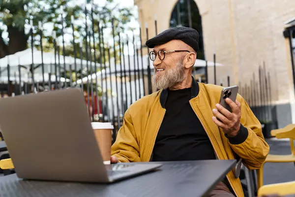A fashionable senior man relaxes at an outdoor cafe, surrounded by urban charm. — Stock Photo