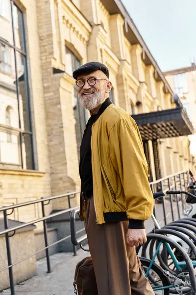 A fashionable senior man confidently walks along the bustling city street. — Stock Photo