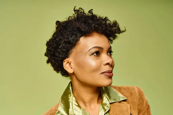 A stunning African American woman poses confidently in her trendy look against green. — Stock Photo