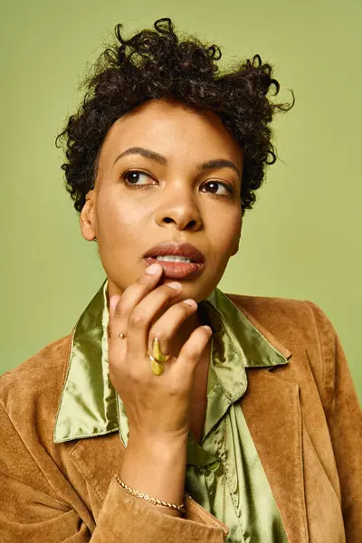 Stylish african american woman poses confidently against a vibrant green backdrop, exuding charm. — Stock Photo