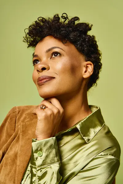 A stylish African American woman poses thoughtfully against a vibrant green backdrop. — Stock Photo