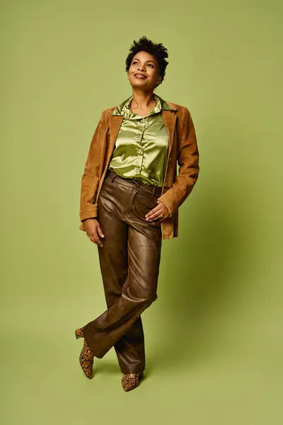 Confident woman poses in chic attire against a lively green backdrop, exuding modern elegance. — Stock Photo