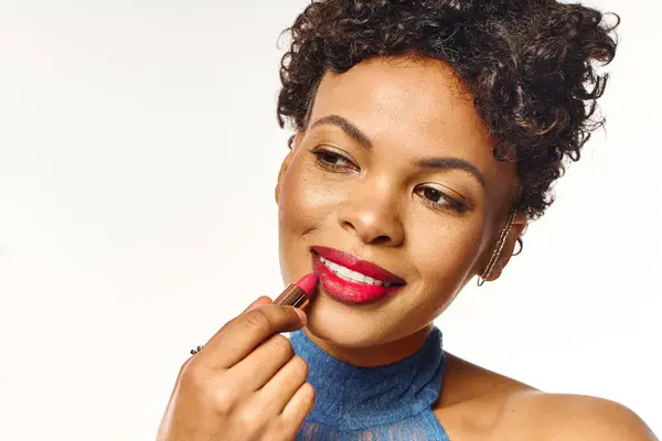 A stylish woman confidently applies bold red lipstick for a special occasion. — Stock Photo