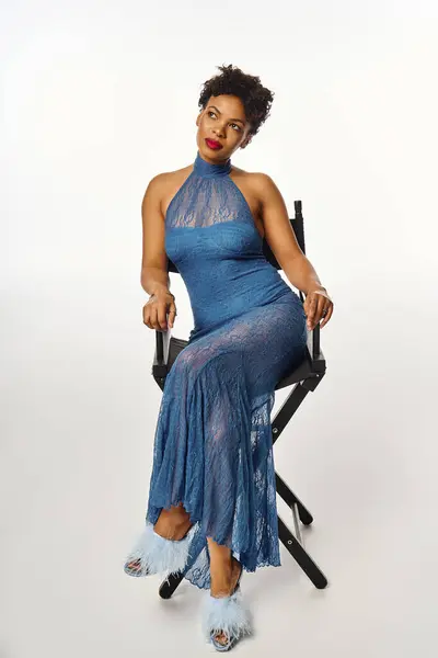 A fashionable african american woman exudes confidence while posing in a beautiful blue dress. — Stock Photo