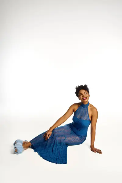 A fashionable woman showcases her chic blue outfit and playful shoes while sitting gracefully. — Stock Photo