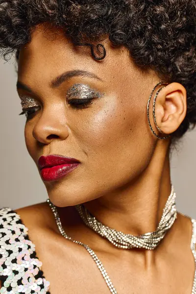 An elegant African American woman poses confidently with striking makeup and stylish jewelry. — Stock Photo