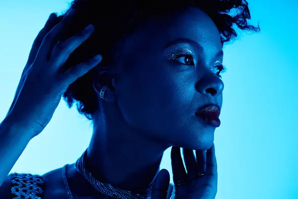A stunning African American woman poses gracefully against a vibrant blue backdrop. — Stock Photo