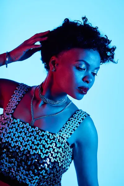 A fashionable african american woman showcases her style with confidence in a vibrant blue setting. — Stock Photo