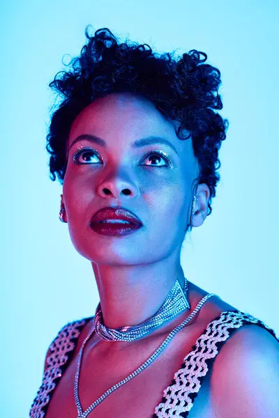 A stylish African American woman with a modern hairstyle gazes up, exuding elegance. — Stock Photo