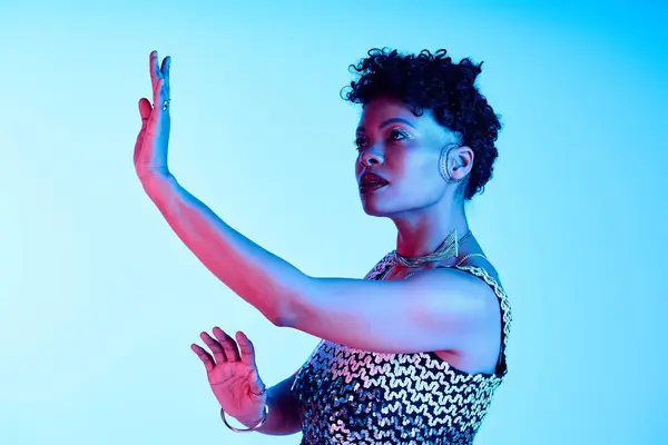 A stylish African American woman poses elegantly with her hand raised in artistic lighting. — Stock Photo