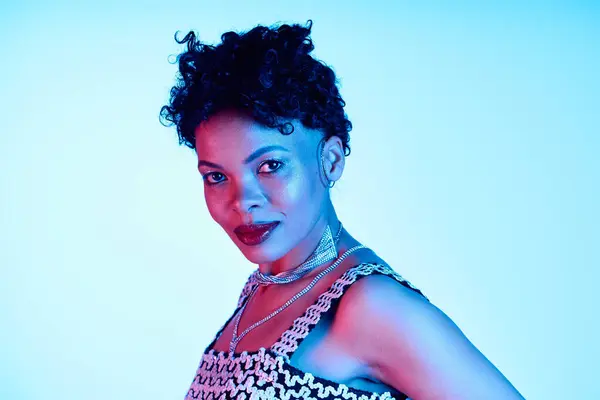 A beautiful African American woman showcases her trendy style with vibrant hues in the background. — Stock Photo