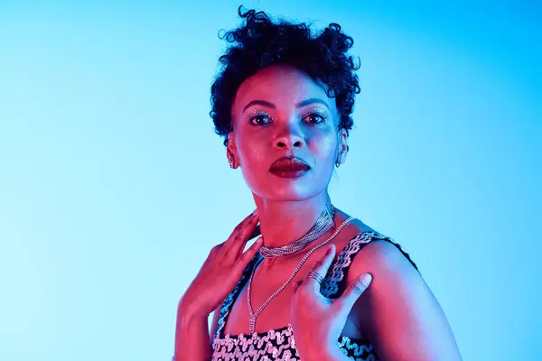 A confident woman embodies modern fashion with bold styles and striking poses in vibrant lights. — Stock Photo