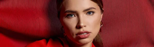 Stylish young woman with captivating features, exuding elegance in a bold red setting. — Stock Photo