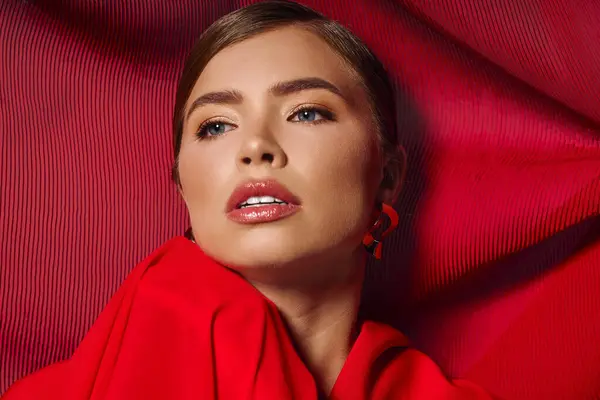 Young and stylish woman captivates with her graceful look, framed by striking red fabric backdrop. — Stock Photo
