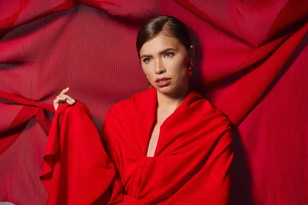 A stylish young woman embraces elegance in a striking red dress. — Stock Photo