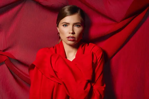 Stylish young woman showcases chic fashion while confidently posing amid bold red drapery — Stock Photo