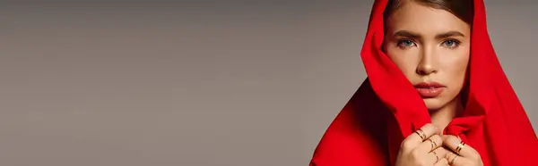 A young beautiful woman showcases her fashion sense wearing a striking red hood, posing gracefully. — Stock Photo