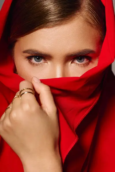 Young woman in vibrant red fabric captivates with her stylish look and serene gaze. — Stock Photo