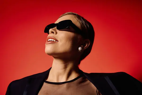Stylish woman looks up gracefully, showcasing elegance in chic sunglasses and attire. — Stock Photo
