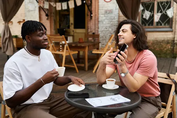Dois homens bonitos desfrutar de uma conversa alegre sobre o café, enquanto sentado em uma mesa de café. — Fotografia de Stock