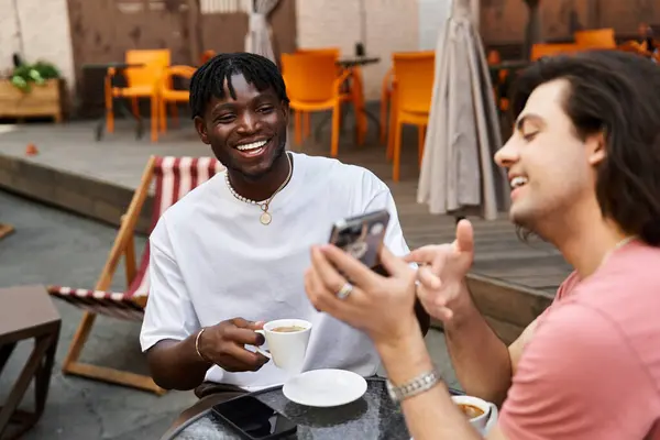 Dois homens compartilham um momento alegre em um café acolhedor, saboreando café e companhia uns dos outros.. — Fotografia de Stock