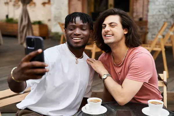 Dois homens bonitos compartilham uma experiência alegre como eles tomam uma selfie em um encontro romântico café. — Fotografia de Stock