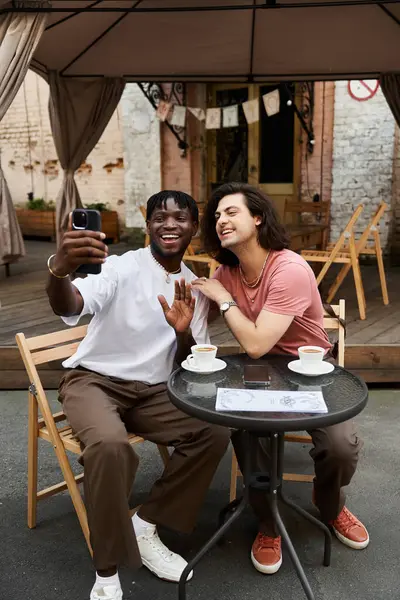 Dois homens amorosos desfrutar de uma data café alegre, compartilhando risos e uma selfie em meio ao charme. — Fotografia de Stock