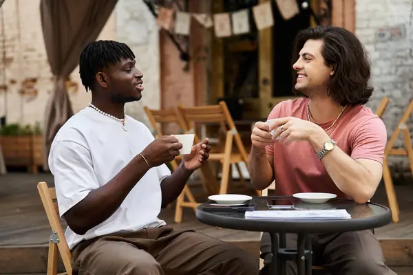 Deux beaux hommes partagent sourires et rires autour d'un café assis dans un charmant café. — Photo de stock