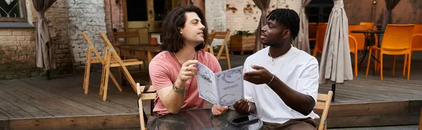 Two handsome men share laughter and love while browsing the menu at their favorite cafe. — Stock Photo