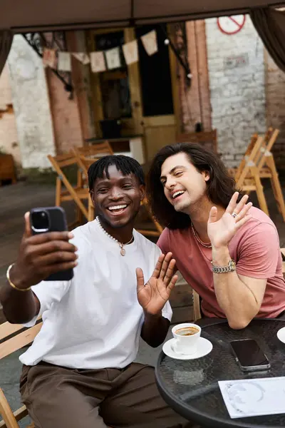 Two loving men enjoy a warm moment together at a cozy cafe while taking a selfie. — Stock Photo