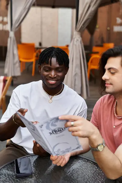 Ein liebevolles homosexuelles Paar teilt einen freudigen Moment beim Blick über die Speisekarte in einem einladenden Café. — Stockfoto
