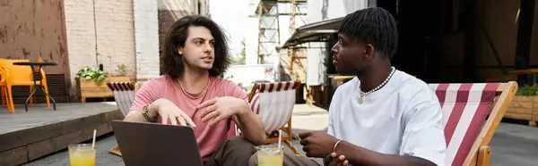 Dois homens bonitos compartilham risos e conversas profundas enquanto desfrutam de bebidas em um terraço ensolarado com café. — Fotografia de Stock
