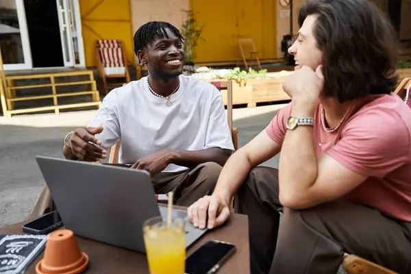 Two loving partners share laughter and connection over drinks while working on a laptop in a cafe — Stock Photo