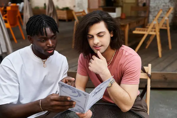 A loving gay couple enjoys each others company while browsing the menu in a warm cafe atmosphere. — Stock Photo