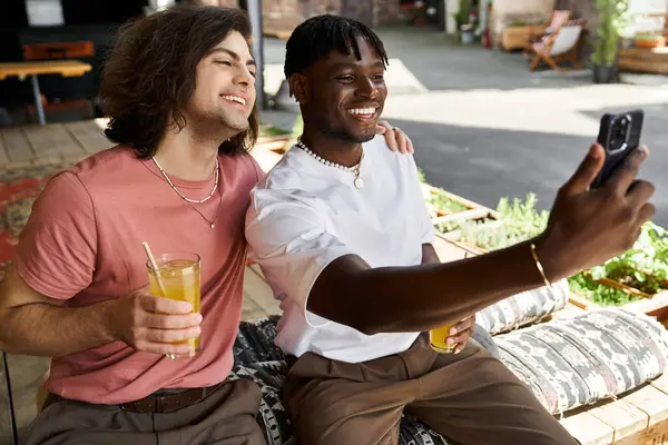 Two attractive people laugh and toast while snapping a selfie on a lovely cafe date. — Stock Photo