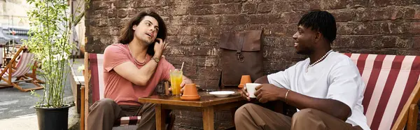 Um casal gay amoroso compartilha risos e bebidas em um ambiente de café quente, imerso em conversa. — Fotografia de Stock