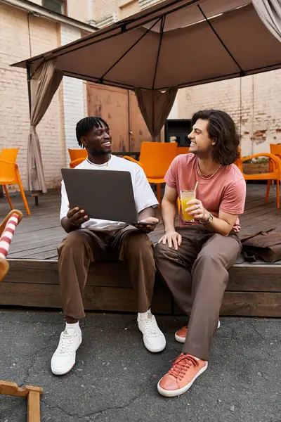 Dois homens bonitos desfrutar uns dos outros companhia em um café ao ar livre, bebendo bebidas e conversando calorosamente. — Fotografia de Stock