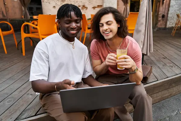 Um casal compartilha um momento aconchegante café, rindo sobre bebidas e um laptop. — Fotografia de Stock