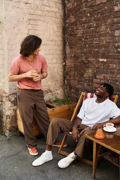 Two loving men share laughter and drinks at a quaint cafe, creating cherished memories together. — Stock Photo