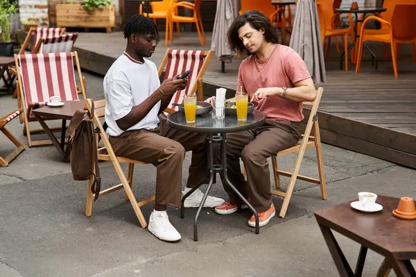 Dois homens bonitos compartilham risos e bebidas enquanto desfrutam de um encontro romântico ao ar livre no café. — Fotografia de Stock