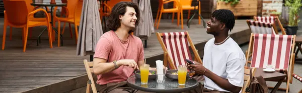 Dois homens felizes compartilham risos e bebidas em um café vibrante, desfrutando de seu encontro romântico juntos. — Fotografia de Stock